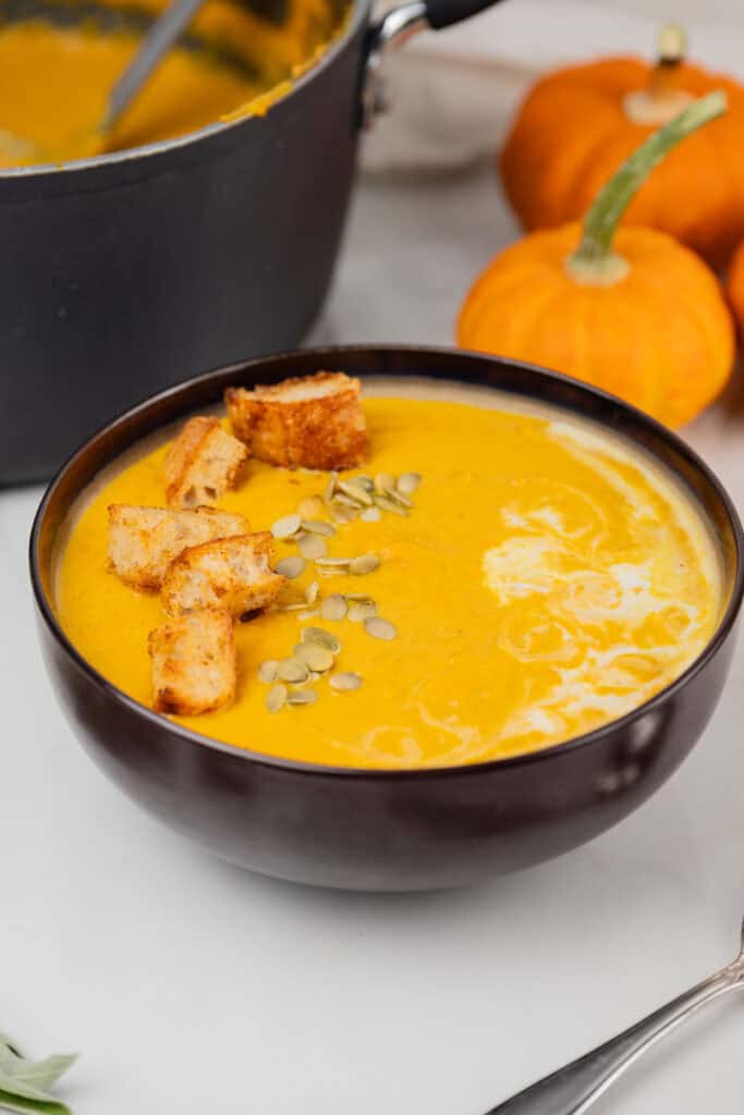 Bowl of pumpkin soup with croutons and pumpkin seeds.