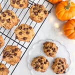 Pumpkin chocolate chip cookies cooling on a wire rack and served on a clear plate.